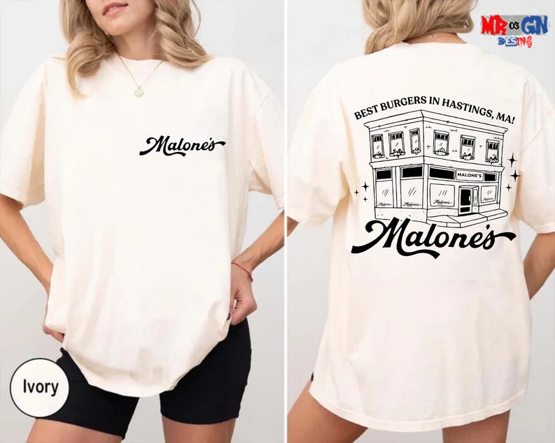 A white t-shirt with a graphic design on the back, depicting a building and the text "Best Burgers in Hastings, MA" printed on it.