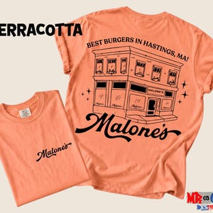 a t-shirt with a graphic design of a building and the text "Malone's" printed on it.