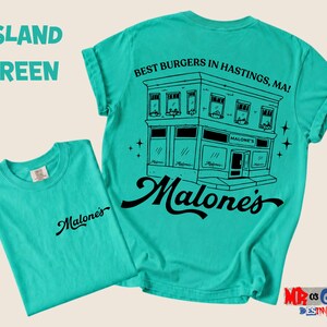 A turquoise t-shirt with a graphic design of a building and text, along with the text "Malone's" and "Best Burgers in Hastings, MA!" printed on it.