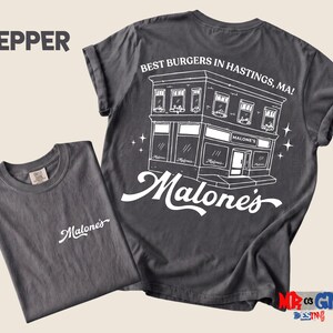 a gray t-shirt with a graphic design on the back, depicting a building and the text "Pepper" and "Best Burgers in Hastings, MA!"