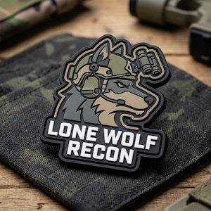 May include: A tactical morale patch featuring a stylized wolf head wearing a combat helmet with night vision goggles and a headset. The design uses olive green, tan, and black colors. The text LONE WOLF RECON is printed in bold white letters.