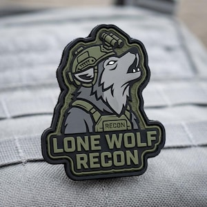 May include: A tactical morale patch featuring a gray wolf wearing a green military helmet and vest. The wolf is howling, and the text LONE WOLF RECON is displayed in bold green letters at the bottom, with the word RECON also on the vest.