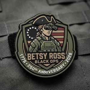 May include: A circular patch with a shield design featuring a woman wearing a tricorn hat and binoculars, with the text "BETSY ROSS BLACK OPS 250th ANNIVERSARY 1776-2026". The patch has a black, green, and tan color scheme.