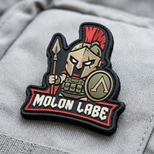 May include: A black, red, and tan patch featuring a cartoon Spartan warrior holding a spear and shield. The patch has the words "MOLON LABE" in white text on a red banner.