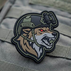 May include: A tactical patch featuring a snarling wolf wearing a military helmet with night vision goggles. The patch is primarily black, brown, and green, with red eyes. The wolf's head is the central design element.