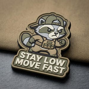 May include: A tan, olive green, and gray patch featuring a cartoon raccoon wearing a hat and tactical vest. The raccoon has an angry expression and is running. The text "STAY LOW MOVE FAST" is below the raccoon.