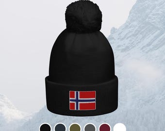 May include: Black knit beanie with a matching pom-pom. The hat features an embroidered Norwegian flag on the front. Available in multiple colors, this winter hat is a cozy accessory.