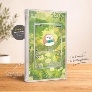 Könnte beinhalten: Ein transparenter Acryl-Bilderrahmen mit einer Bauz-Sammelkarte. Der Rahmen hat einen grünen Wald-Hintergrund mit Illustrationen von Blättern und Blumen. Der Text auf dem Rahmen lautet KRISTALLKLAR & STRAHLENDE FARBEN, Zeige deine Karten im besten Case! sowie Für Sammler. Für Lieblingskarten.