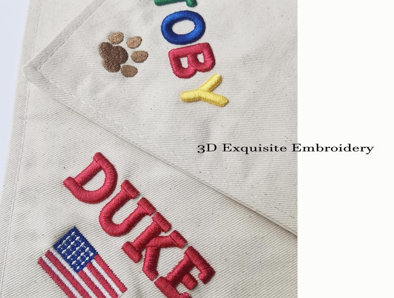 May include: Off-white fabric featuring 3D embroidery of the names TOBY and DUKE in colourful block letters. TOBY is accompanied by a brown paw print, while DUKE is paired with a small American flag. The text 3D Exquisite Embroidery is visible.