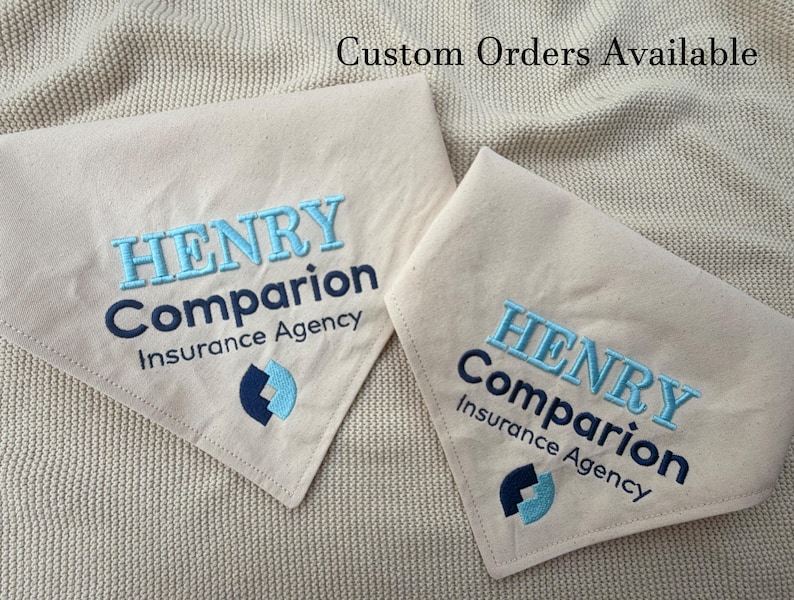 May include: Two triangular beige fabric bandanas featuring embroidered text that reads HENRY Companion Insurance Agency in light blue and dark blue thread, accompanied by a matching logo. The text Custom Orders Available is visible.