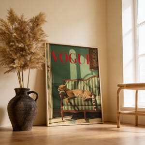 Puede incluir: Una portada enmarcada de la revista Vogue con un guepardo descansando en un sill&oacute;n a rayas verdes y blancas. La palabra "VOGUE" est&aacute; en letras rojas. Un jarr&oacute;n grande y oscuro con plantas secas en primer plano.