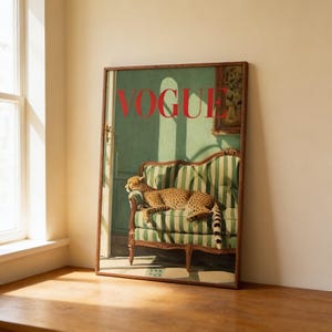 Puede incluir: Impresi&oacute;n enmarcada con la palabra "VOGUE" en letras rojas. La obra de arte representa un guepardo descansando en un sof&aacute; a rayas verdes y blancas. El fondo es una habitaci&oacute;n de tonos verdes con una ventana y una peque&ntilde;a pintura.