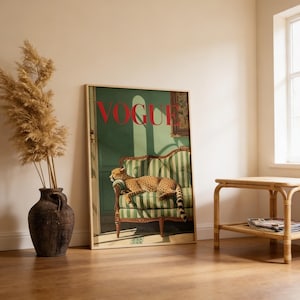 Puede incluir: Una portada enmarcada de la revista Vogue con un guepardo descansando en un sof&aacute; a rayas verdes y blancas. La palabra "VOGUE" est&aacute; en rojo. La obra de arte se exhibe en una habitaci&oacute;n con un jarr&oacute;n de plantas secas y una peque&ntilde;a mesa de madera.