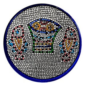 May include: Round mosaic tile with a blue border. The mosaic features a central basket design with colorful flowers and two stylized fish on either side. The mosaic is made of small, square tiles in various colors, including pink, yellow, blue, and green.