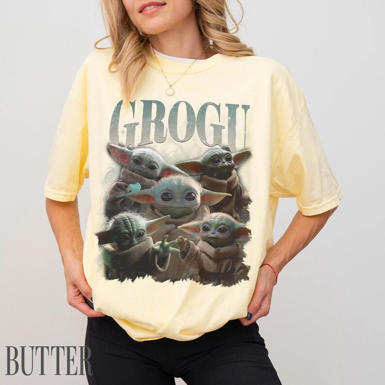 K&ouml;nnte beinhalten: Hellgelbes T-Shirt mit einem Aufdruck von Grogu, auch bekannt als Baby Yoda, aus der Star Wars-Reihe. Das Wort "GROGU" ist &uuml;ber dem Bild von Grogu aufgedruckt. Das T-Shirt wird getragen.