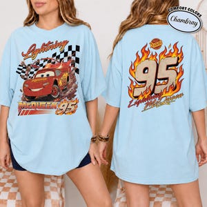 May include: Light blue t-shirt featuring Lightning McQueen from the movie Cars. The front graphic shows McQueen racing with the text "Lightning McQueen 95". The back displays "95" in flames with "Lightning McQueen" below.