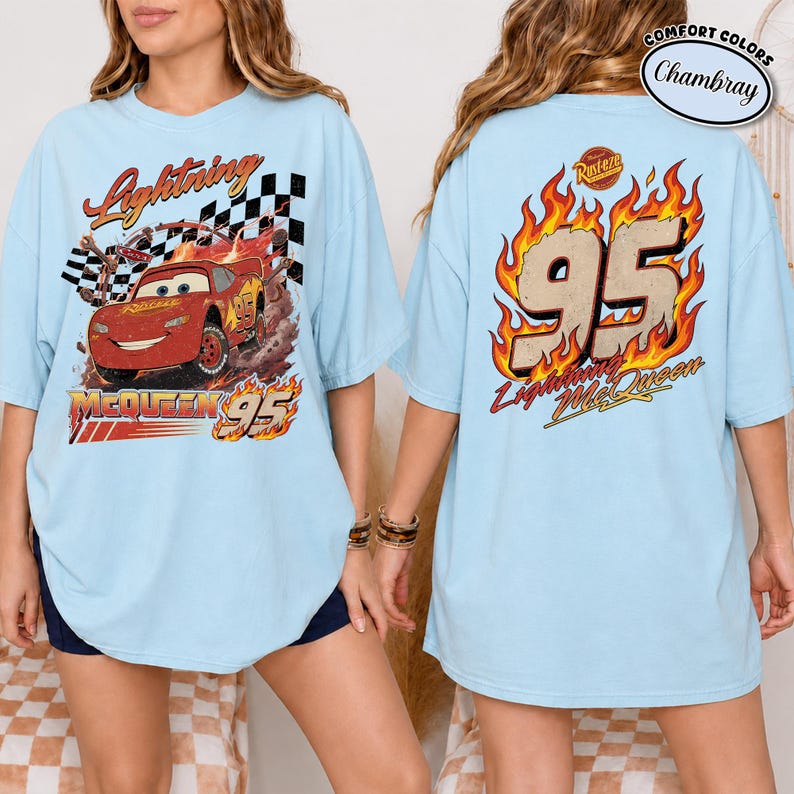 May include: Light blue t-shirt featuring Lightning McQueen from the movie Cars. The front graphic shows McQueen racing with the text "Lightning McQueen 95". The back displays "95" in flames with "Lightning McQueen" below.