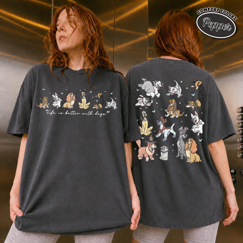 Puede incluir: Camiseta gris oscuro Comfort Colors con ilustraciones de perros de dibujos animados. La parte delantera muestra la frase "life is better with dogs". La parte trasera de la camiseta tiene m&aacute;s ilustraciones de perros. La camiseta tiene un corte relajado.