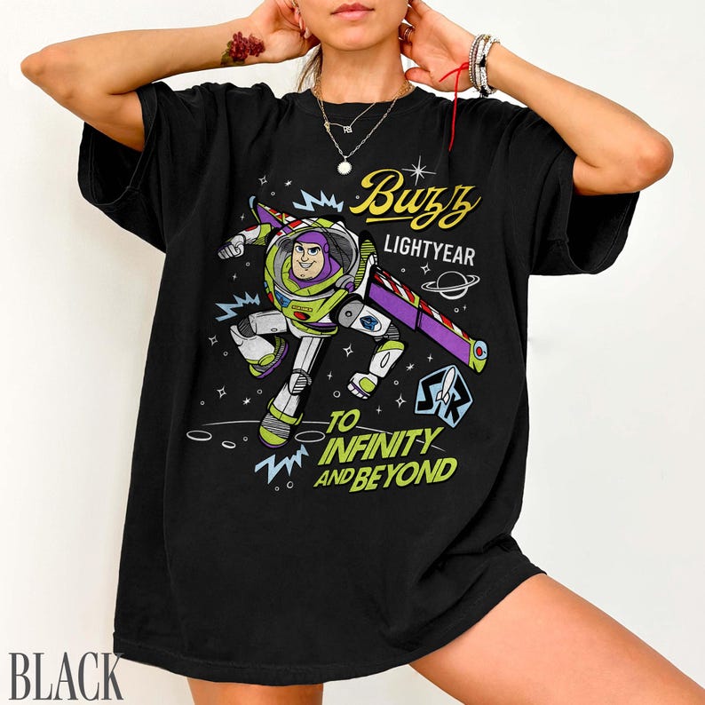 Pode incluir: Camiseta preta com um gr&aacute;fico de Buzz Lightyear em pose de voo, com as palavras "Buzz Lightyear" e "To Infinity and Beyond". O design inclui um tema espacial com estrelas e planetas.
