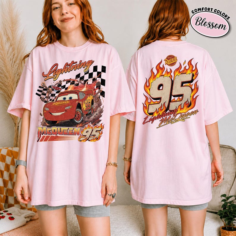 May include: Light pink t-shirt featuring Lightning McQueen from the Cars movie. The front graphic shows McQueen racing with the text "Lightning McQueen 95". The back of the shirt displays "95" in flames with "Lightning McQueen" below.