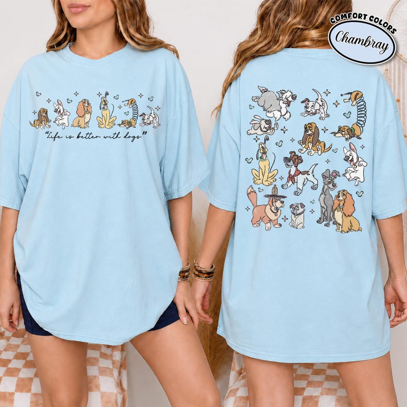 Puede incluir: Camiseta azul claro con ilustraciones de perros. La parte delantera presenta una fila de diferentes razas de perros con la frase "Life is better with dogs." La parte trasera de la camiseta muestra m&aacute;s dibujos de perros. La camiseta tiene mangas cortas y un corte holgado.