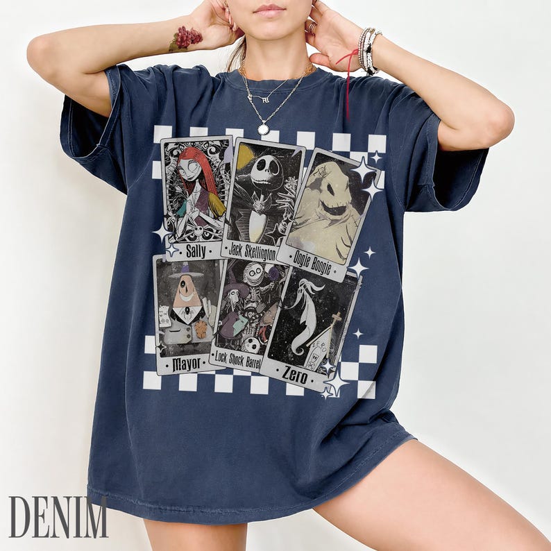 May include: Navy blue t-shirt featuring character cards from The Nightmare Before Christmas. The cards include Sally, Jack Skellington, Oogie Boogie, Mayor, Lock Shock Barrel, and Zero. The word "DENIM" is printed at the bottom.