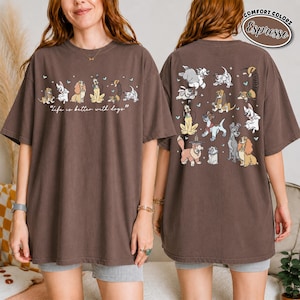 Puede incluir: Camiseta color espresso con dise&ntilde;o de perros. La parte delantera muestra perros de dibujos animados y el texto "Life is better with dogs". La parte trasera muestra varias ilustraciones de perros. La camiseta tiene mangas cortas y un corte holgado.