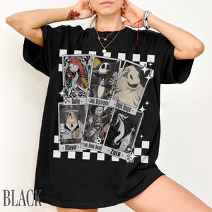 May include: Black t-shirt featuring playing card designs with characters from The Nightmare Before Christmas. The cards include Sally, Jack Skellington, Oogie Boogie, Mayor, Lock, Shock, Barrel, and Zero. The word "BLACK" is printed at the bottom.