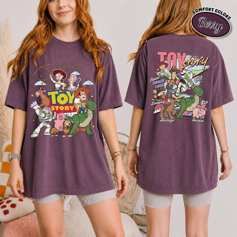 K&ouml;nnte beinhalten: Ein beerenfarbenes T-Shirt mit dem Toy Story-Logo und -Charakteren. Auf der Vorderseite des Shirts sind Woody, Buzz Lightyear und andere Charaktere abgebildet. Auf der R&uuml;ckseite des Shirts befinden sich das Toy Story-Logo und weitere Charaktere. Das Shirt besteht aus einem bequemen Material.