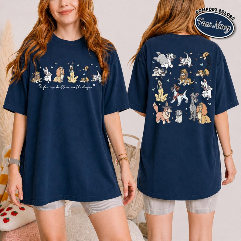 Puede incluir: Camiseta azul marino con ilustraciones de perros de dibujos animados en la parte delantera y trasera. La parte delantera muestra el texto "Life is better with dogs". La parte trasera muestra varias razas de perros.
