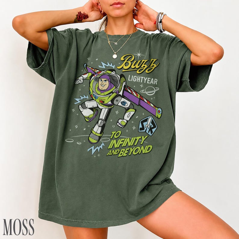 Pode incluir: T-shirt verde musgo com um gr&aacute;fico de Buzz Lightyear de Toy Story. O design inclui o texto "Buzz Lightyear" e "To Infinity and Beyond". A camisa tem um ajuste folgado.