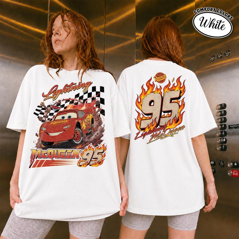 May include: White t-shirt featuring Lightning McQueen from the Cars movie. The front graphic shows McQueen racing with the text "Lightning McQueen 95". The back of the shirt displays "95" in flames and the text "Lightning McQueen".