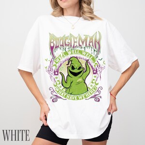 May include: White t-shirt with a green Oogie Boogie graphic, the text "BOOGIEMAN", and "WELL WELL WELL! WHAT HAVE WE HERE?". The design incorporates purple and green elements, and bat silhouettes.