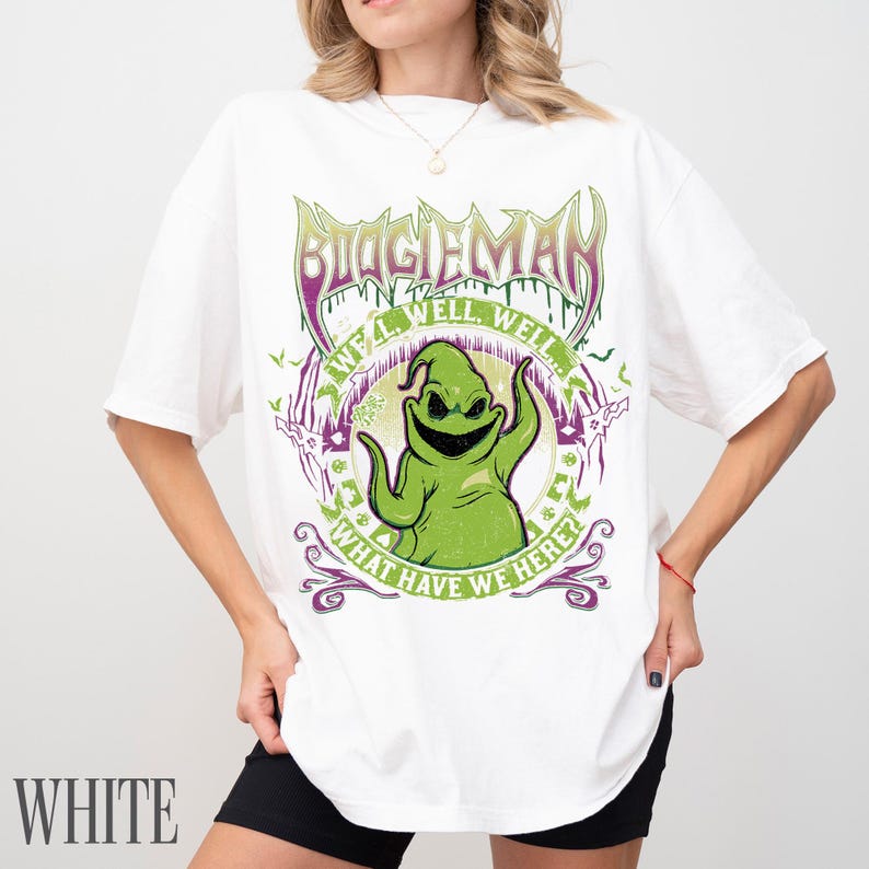 May include: White t-shirt with a green Oogie Boogie graphic, the text "BOOGIEMAN", and "WELL WELL WELL! WHAT HAVE WE HERE?". The design incorporates purple and green elements, and bat silhouettes.