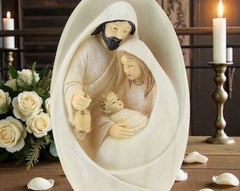 May include: A cream-colored religious figurine depicting the Holy Family: Joseph, Mary, and baby Jesus. Joseph holds a lantern. The figures are enclosed within an oval frame. The scene is set on a wooden surface with candles and flowers in the background.