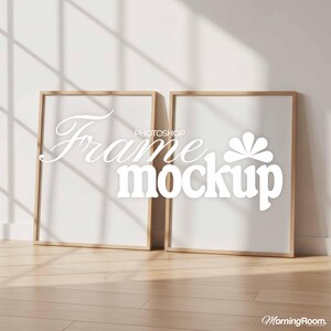 May include: Two rectangular wooden frames with white interiors are propped against a white wall. The frames are empty, with the text "Frame mockup" overlaid in white. The frames are on a wooden floor.