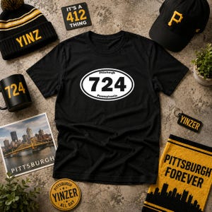 May include: A black t-shirt featuring a white oval graphic with the text Pittsburgh 724 Pennsylvania, surrounded by a black beanie with YINZ, a black cap with a yellow P, a black mug with 724, a Pittsburgh photo, a YINZER keychain, and a yellow towel.