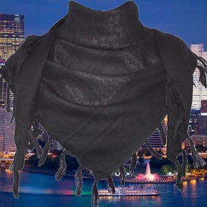 May include: A black keffiyeh scarf with a textured pattern and fringed edges. The scarf is draped, showcasing its triangular shape. The background features a cityscape with a body of water and a fountain.