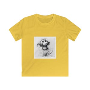 May include: A yellow t-shirt featuring a black and white illustration of a monkey wearing a tutu. The monkey is looking upwards with a smile. The t-shirt is made of a soft, comfortable material.