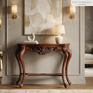 May include: A dark brown, ornate console table with curved legs and carved floral details. A small white lamp and decorative objects sit on the table. The wall behind the table is painted a light gray color. The Furnique Woodworks logo is in the top right corner.