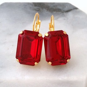 May include: A pair of gold earrings with large, red, emerald-cut crystals.