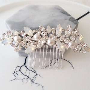 May include: A silver bridal hair comb with a floral design featuring white opal and pearl accents.