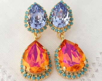 May include: A pair of dangle earrings with two teardrop-shaped crystals. The top crystal is light blue and the bottom crystal is orange with a pink iridescent sheen. Both crystals are surrounded by a turquoise colored bead border.