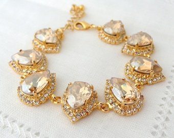 May include: A gold bracelet with a teardrop-shaped crystal design. The crystals are clear with a light champagne hue and are set in gold.