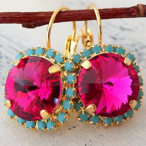Może przedstawiać: Złote kolczyki koła z dużym, jasnoróżowym kryształem otoczonym halo turkusowych koralików.