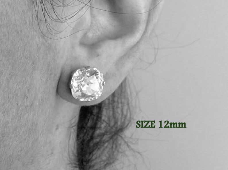 Puede incluir: Primer plano de una oreja con un pendiente de cristal transparente. El pendiente tiene un tama&ntilde;o de 12 mm. SIZE 12mm est&aacute; escrito en verde debajo del pendiente.
