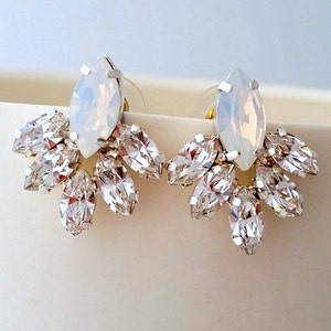 May include: A pair of silver earrings with a large, white, marquise-shaped crystal in the center and smaller, clear, marquise-shaped crystals surrounding it.