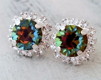 May include: A pair of silver earrings with a round, iridescent green and brown gemstone surrounded by a halo of clear rhinestones.