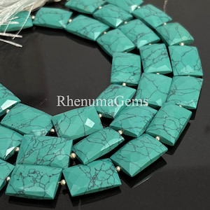 Puede incluir: Primer plano de un collar de cuentas de piedras preciosas turquesas. Las cuentas son rectangulares con bordes facetados y vetas oscuras. Las cuentas están ensartadas con pequeños espaciadores dorados. El texto "RhenumaGems" es visible.