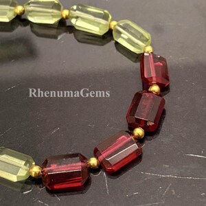 Könnte beinhalten: Ein Armband mit abwechselnd rechteckigen, facettierten hellgelben und tiefroten Edelsteinen, die durch kleine goldfarbene, kugelförmige Perlen getrennt sind. Der Text RhenumaGems ist auf der linken Seite des Schmuckstücks zu sehen.